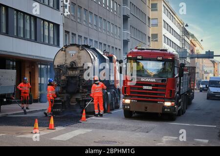 Straßenarbeiten Crew Reparatur alten Asphalt Pflaster in der Stadt. Verkehr mit Scania 124G LKW Schlepper Maschinen vorbei. Helsinki, Finnland. 13.Mai 2020. Stockfoto