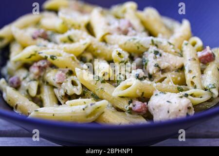 Italienischer Speck und Parmesan Penne Pasta mit Huhn in einer Schüssel. Nahaufnahme mit selektivem Fokus und geringer Schärfentiefe. Stockfoto