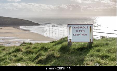 Ein weitläufiger Strand an der Küste von South Wales, Großbritannien an einem hellen Wintertag. Es gibt ein Schild, das sagt: 'Gefährliche Klippen, halten Sie sich fern' Stockfoto