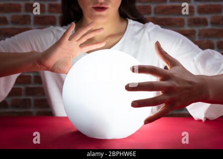 Nahaufnahme der Wahrsager Hand über die glühende Glaskugel Rot Schreibtisch Stockfoto