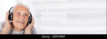Lächelnd Senior Frau Hören von Musik über Kopfhörer Stockfoto
