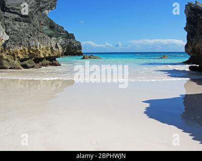 Eine idilische tropische Bucht, mit klarem Meer, das auf dem glatten Sand lappt Stockfoto