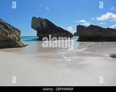 Eine idilische tropische Bucht, mit klarem Meer, das auf dem glatten Sand lappt Stockfoto