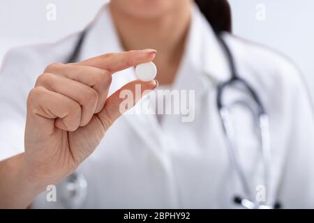 In der Nähe der weiblichen Doktor mit Stethoskop um den Hals halten weiße Tablette in der Hand Stockfoto