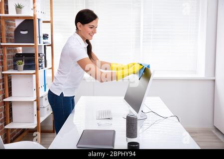 Nahaufnahme von einer Person Hand Reinigung Desktop Bildschirm mit blauem Rag im Büro Stockfoto