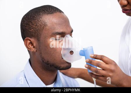 Junge weibliche Inverkehrbringen Inhaler Maske auf dem Mund auf weißem Hintergrund Stockfoto