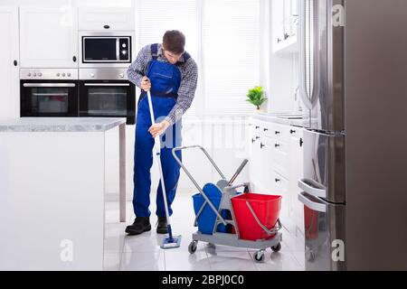 Männliche Hausmeister Reinigung Boden mit Mop In der Küche Stockfoto