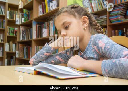 Ein Mädchen von zehn Jahre alt ist, ein Buch zu lesen im Lesesaal Stockfoto