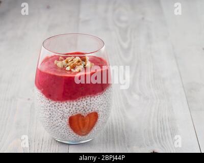 Idee für gesundes Frühstück am Valentinstag: Chia Pudding mit roten Beeren Püree, gehackte Mandeln auf und Erdbeere in der Form des Herzens. Kopieren Sie sp Stockfoto