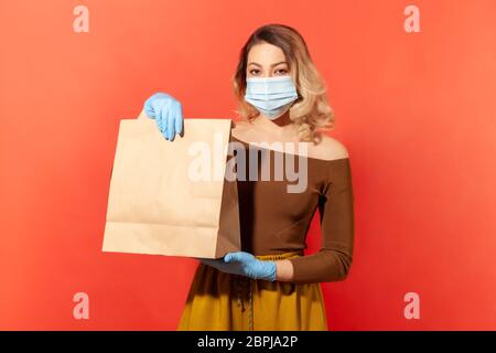 Bleiben Sie zu Hause, Einkaufen sicher. Frau in Schutzmaske und Handschuhe halten Papiertüte, Lebensmittel Kauf Lieferung in Coronavirus Selbstisolierung, Online-Bestellung fo Stockfoto