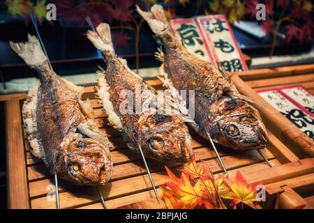 Gegrillte Fische auf Stöcken als Street Food auf dem Nishiki Markt in Kyoto, Japan Stockfoto