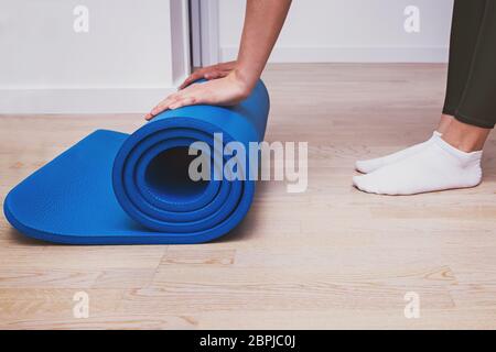 Frau rollt ihre Matte nach einem Yoga-Kurs oder Training zu Hause. Stockfoto