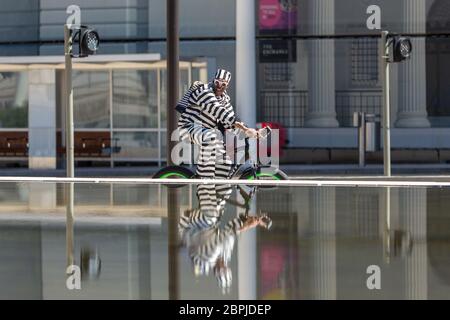 Birmingham, Großbritannien. Mai 2020. Ein stilvoll gekleideter Radfahrer fährt auf dem Centenary Square im Stadtzentrum von Birmingham um die Brunnen herum. Quelle: Peter Lopeman/Alamy Live News Stockfoto