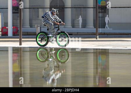 Birmingham, Großbritannien. Mai 2020. Ein stilvoll gekleideter Radfahrer fährt auf dem Centenary Square im Stadtzentrum von Birmingham um die Brunnen herum. Quelle: Peter Lopeman/Alamy Live News Stockfoto