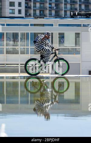 Birmingham, Großbritannien. Mai 2020. Ein stilvoll gekleideter Radfahrer fährt auf dem Centenary Square im Stadtzentrum von Birmingham um die Brunnen herum. Quelle: Peter Lopeman/Alamy Live News Stockfoto