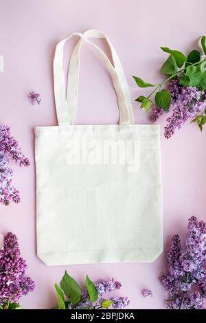 Eco Tasche liegt auf dem rosa Hintergrund mit schönen lila Blumen Stockfoto