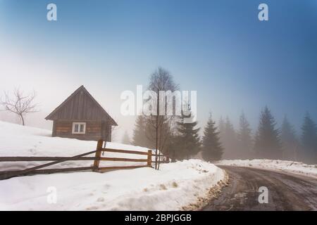 Einsame Haus in Bergdorf. Nebel und Schnee auf dem Berg Landstraße in den Karpaten. Wettervorhersage für frühen Frühling. Feder comi Stockfoto