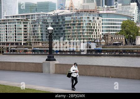 Mann mit Gesichtsmaske bei More London, der über den Fluss in Richtung City of London blickt, Das normalerweise von Touristen frequentiert wird, ist in leeren Straßen unheimlich ruhig und still, während die Blockierung andauert und die Menschen die Botschaft des Aufenthalts zu Hause in der Hauptstadt am 11. Mai 2020 in London, England, Großbritannien, beobachten. Coronavirus oder Covid-19 ist eine neue Atemwegserkrankung, die bisher beim Menschen nicht beobachtet wurde. Während ein Großteil oder Europa in den Lockdown gebracht wurde, hat die britische Regierung nun eine leichte Lockerung der strengen Regeln als Teil ihrer langfristigen Strategie angekündigt, insbesondere der Socia Stockfoto