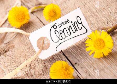Weißes Etikett Mit Englischer Kalligraphie Spring Cleaning. Löwenzahn-Blüte Auf Rustikalem Holzhintergrund Stockfoto