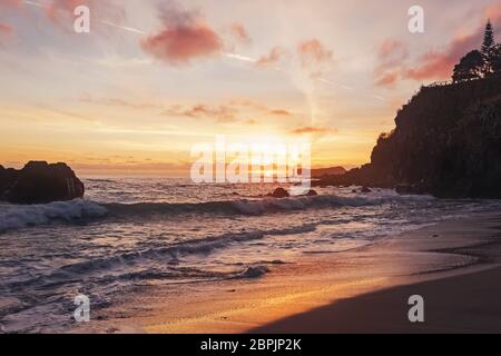 Schöner Sonnenuntergang am Strand mit schwarzem vulkanischen Sand Stockfoto