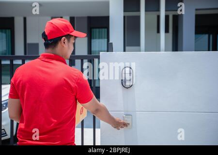 Asiatische Lieferung Soldaten tragen eine rote Uniform mit einer roten Kappe Handhabung Kartons, um den Kunden vor dem Haus zu geben und klicken Sie auf die Do Stockfoto
