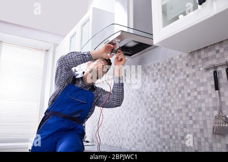 Heimwerker Kontrolle Abzugshaube Filter mit Multimeter in Küche Stockfoto