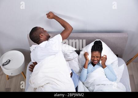 Eine Ansicht von Paar liegend auf Bett gestört durch Lärm Stockfoto