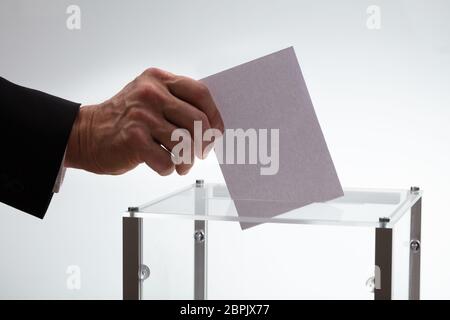 Nahaufnahme der Geschäftsmann Hand Stimmzettel in einem Glaskasten einfügen Stockfoto