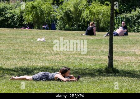 Finsbury Park, Nord London, UK 19 May 2020 - EINE Frau entspannt sich im Finsbury Park, Nord London an einem warmen und sonnigen Tag in London. Die Regierung hat die Regeln für die Sperrung des COVID-19 gelockert, wodurch die Menschen mehr Zeit im Freien verbringen können, während sie die sozialen Distanzierungsrichtlinien befolgen. Laut Met Office werden für morgen 27 Grad celsius prognostiziert. Kredit: Dinendra Haria/Alamy Live News Stockfoto