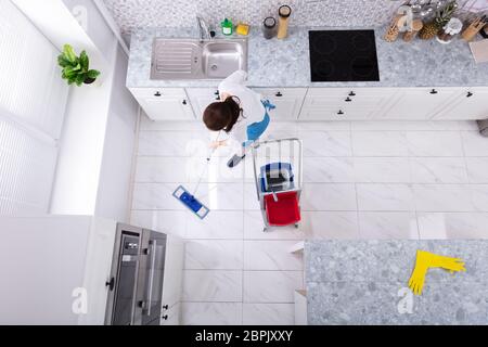 Gerne weibliche Hausmeister Reinigung Boden mit Mop In der Küche Stockfoto