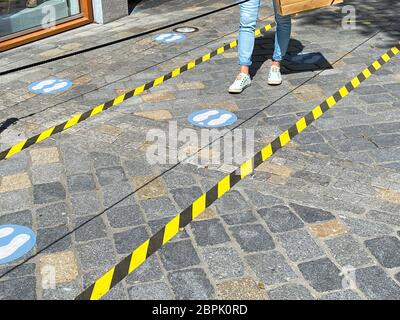 Roermond, Niederlande - Mai 19. 2020: Blick auf die Füße einer Person zwischen nicht quer Bänder und blaue Markierungen Abstand am Ladeneingang in cor zu halten Stockfoto