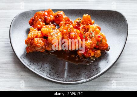 Koreanische, Chinesische Küche - oben Blick auf Kkanpunggi würziger Knoblauch gebratene Hähnchenteile mit Gemüse in süßen Soße auf schwarze Platte Nahaufnahme Stockfoto