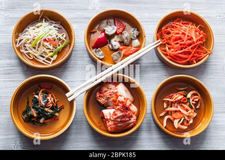 Die koreanische Küche - essstäbchen auf Schüsseln mit verschiedenen Beilagen (Banchan oder panchan) auf Graue Tabelle Stockfoto