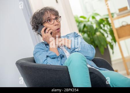 Charmante Frau mittleren Alters mit Brille durch und sprechen Tel. Stockfoto