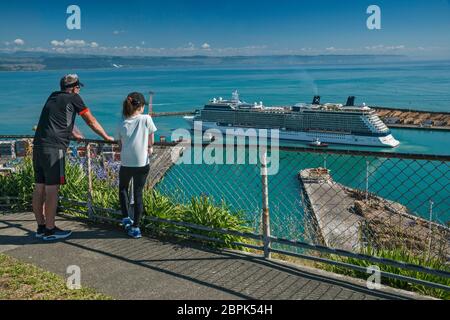 Älterer Mann und junges Mädchen beobachten Celebrity Solstice Kreuzfahrtschiff in Port of Napier, Hawke's Bay Region, North Island, Neuseeland Stockfoto