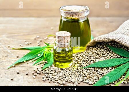 Hanf Öl in zwei Gläser mit Getreide im Sack, Blätter und Stängel von Cannabis auf dem Hintergrund der alten hölzernen Brettern Stockfoto