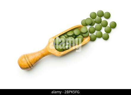 Grüne Chlorella Tabletten oder grüne Gerste pillsin hölzerne Schaufel auf weißem Hintergrund. Stockfoto