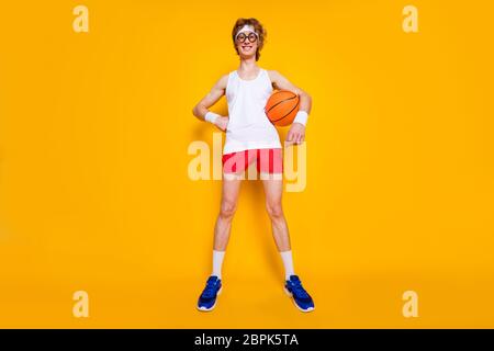 Volle Länge Körpergröße Ansicht von schönen funky erfolgreich fröhlich fröhlichen Kerl in der Hand Orange Ball Amateur Liga Saison isoliert über hell lebendig Stockfoto