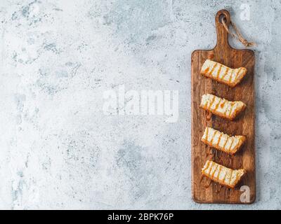 Karamellisierten Käsekuchen Schichten auf hölzernen cuttingboard. Käsekuchen auf grauem Zement Hintergrund mit Kopie Platz für Text. Top View oder flach. Stockfoto