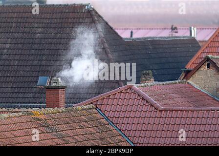 Dächer von einem alten Dorf mit einem rauchenden Schornstein und Copyspace Stockfoto