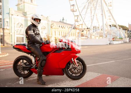 In voller Länge Aufnahme eines Mannes mit schützender Lederjacke und Jeans, auf einem Motorrad in der Stadt sitzen, kopieren Raum Stockfoto