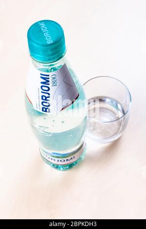 MOSKAU, RUSSLAND - 10. MAI 2020: Plastikflasche von Borjomi und Glas mit Mineralwasser auf hellbraunem Brett. Borjomi ist natürlich kohlensäurehaltiges Mineral Stockfoto