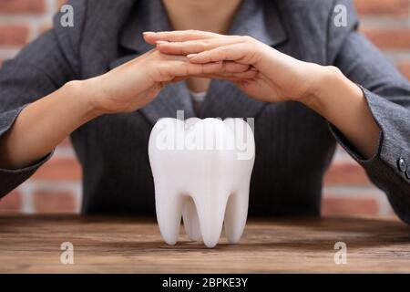 Nahaufnahme von einer Frau, die schützende Hand gesund Hygienische weißen Zahn am Schreibtisch aus Holz Stockfoto