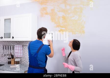 Junge Arbeitnehmer schriftlich über Zwischenablage mit Frau in der Küche Stockfoto