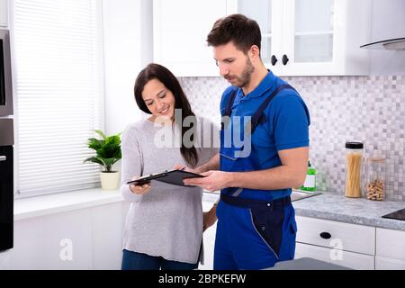 In der Nähe von jungen männlichen Klempner mit Rechnung an die Frau in der Küche Stockfoto