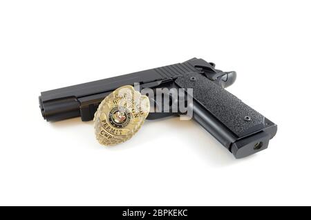 Isoliert über weißem Bild eines Polizeiabzeichens und Handfeuerwaffe für die Strafverfolgung. Stockfoto