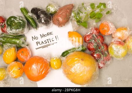 Viele verschiedene Früchte und Gemüse sind in Kunststofffolie verpackte, auf konkreten Hintergrund verpackt Stockfoto