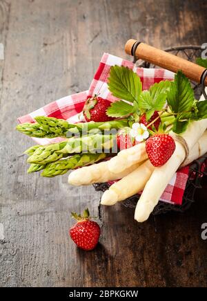 Frische Trauben von Gourmet Grüner und Weißer Spargel Tipps für ein Tuch in einem rustikalen Drahtkorb mit frischen Erdbeeren Stockfoto