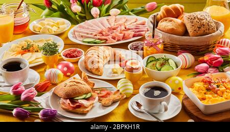 Herz Ostern Frühstück mit Eiern und Tulpen schmücken den Tisch und Brötchen, Croissant, Wurst, Käse, Kaffee für Zwei, Marmelade und Orangensaft Stockfoto