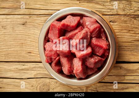 Schneiden Sie Stücke von rohem Fleisch in der Schüssel von oben auf alten rustikalen Holztisch Hintergrund betrachtet Stockfoto